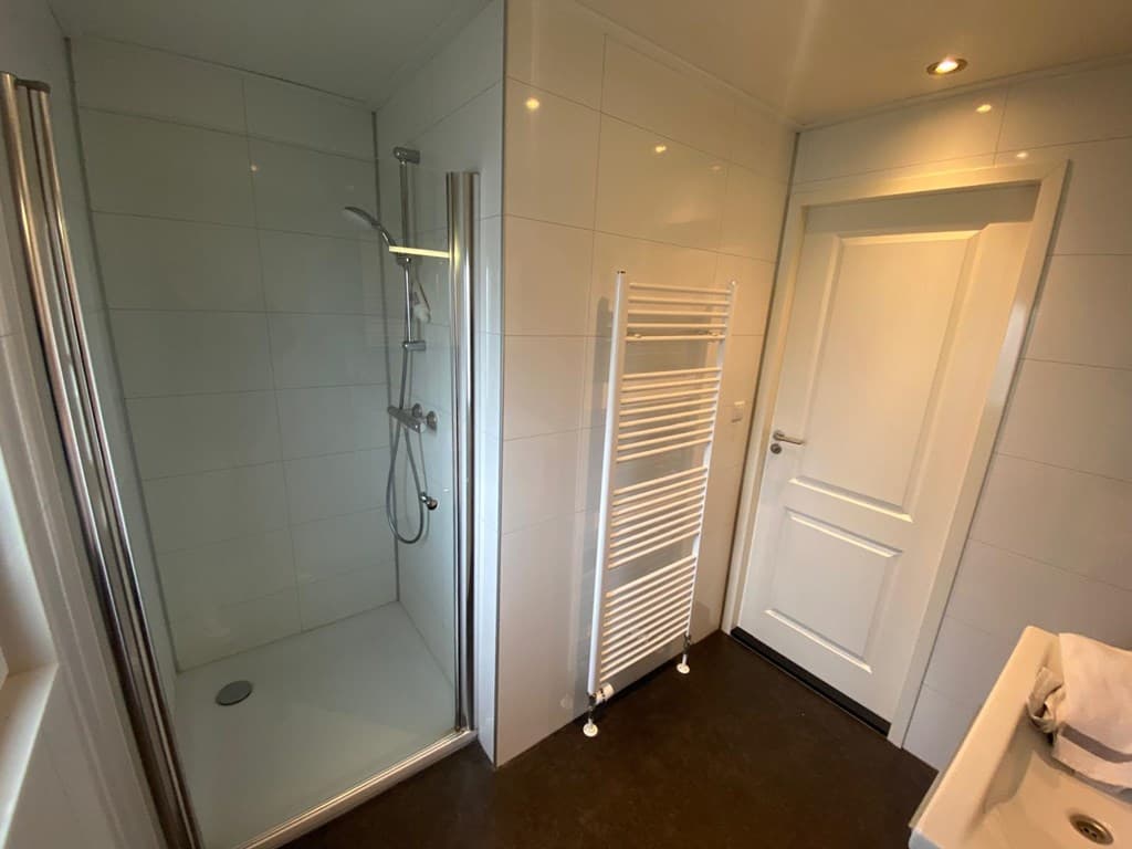 Moderne badkamer met inloopdouche, handdoekradiator en witte wand- en vloertegels