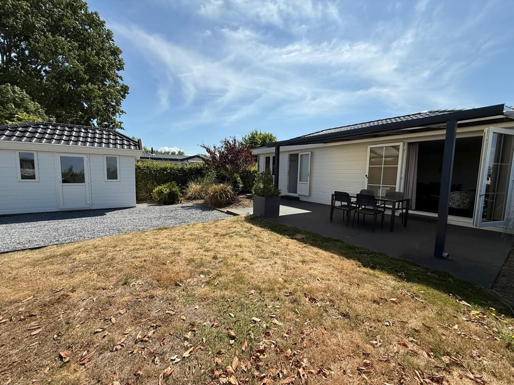 Twee vakantiewoningen met terras en tuin, omringd door groen en grintpad bij EuroParcs De Biesbosch in Dordrecht