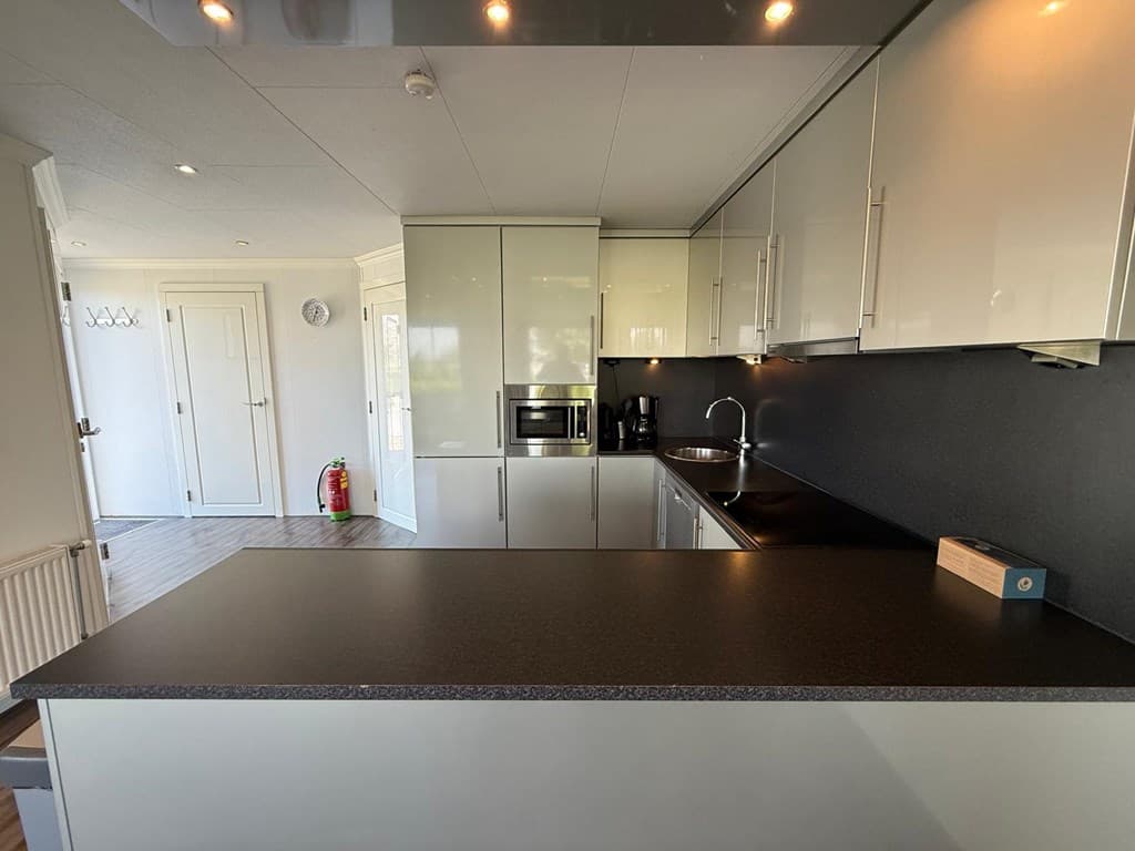Moderne keuken met glanzende kasten, inbouwapparatuur en een zwart aanrechtblad in EuroParcs De Biesbosch.