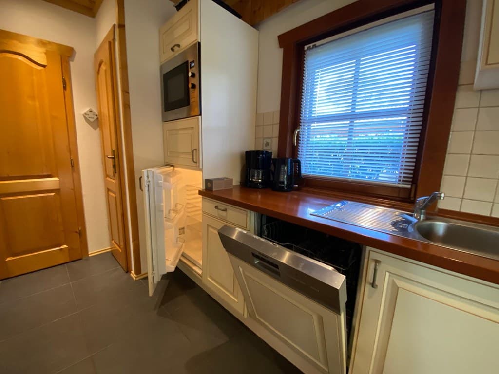 Moderne keuken met inbouwapparatuur, waaronder koelkast, oven, vaatwasser en aanrecht met spoelbak.