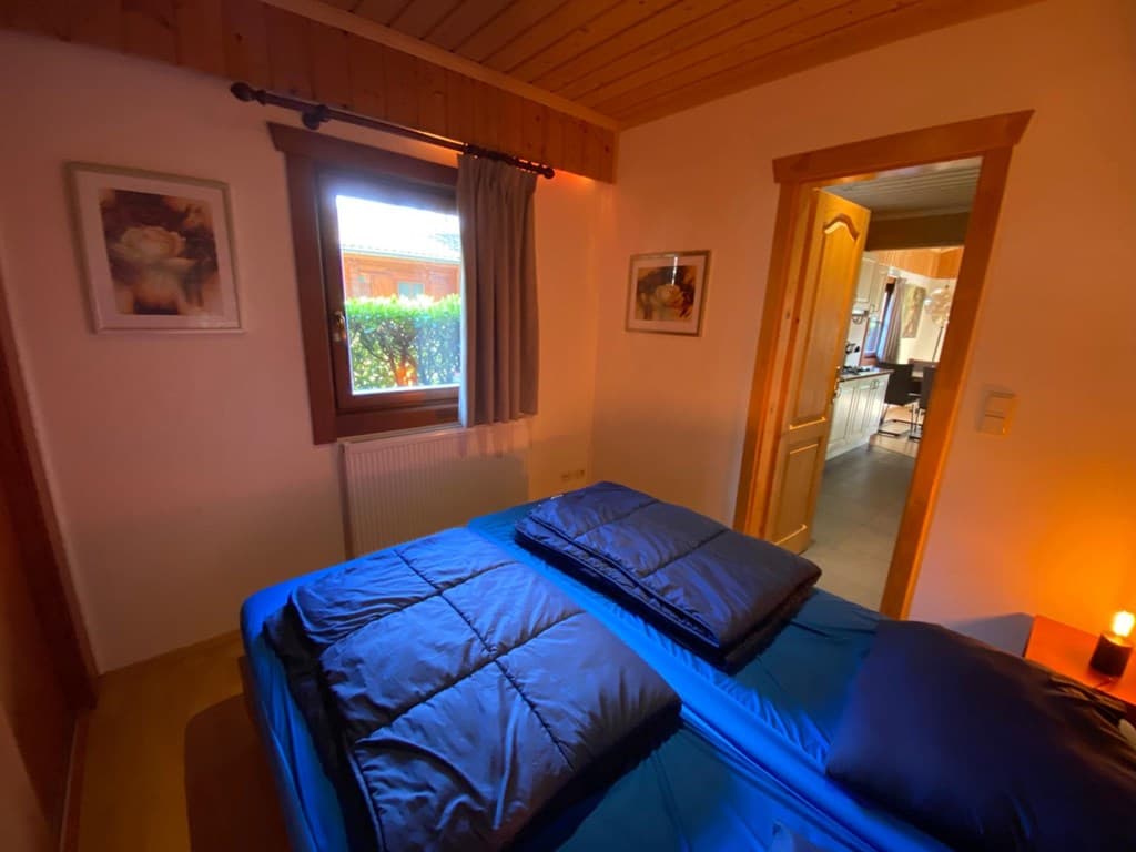 Slaapkamer met twee losse bedden, raam met uitzicht op buiten en sfeervolle verlichting.