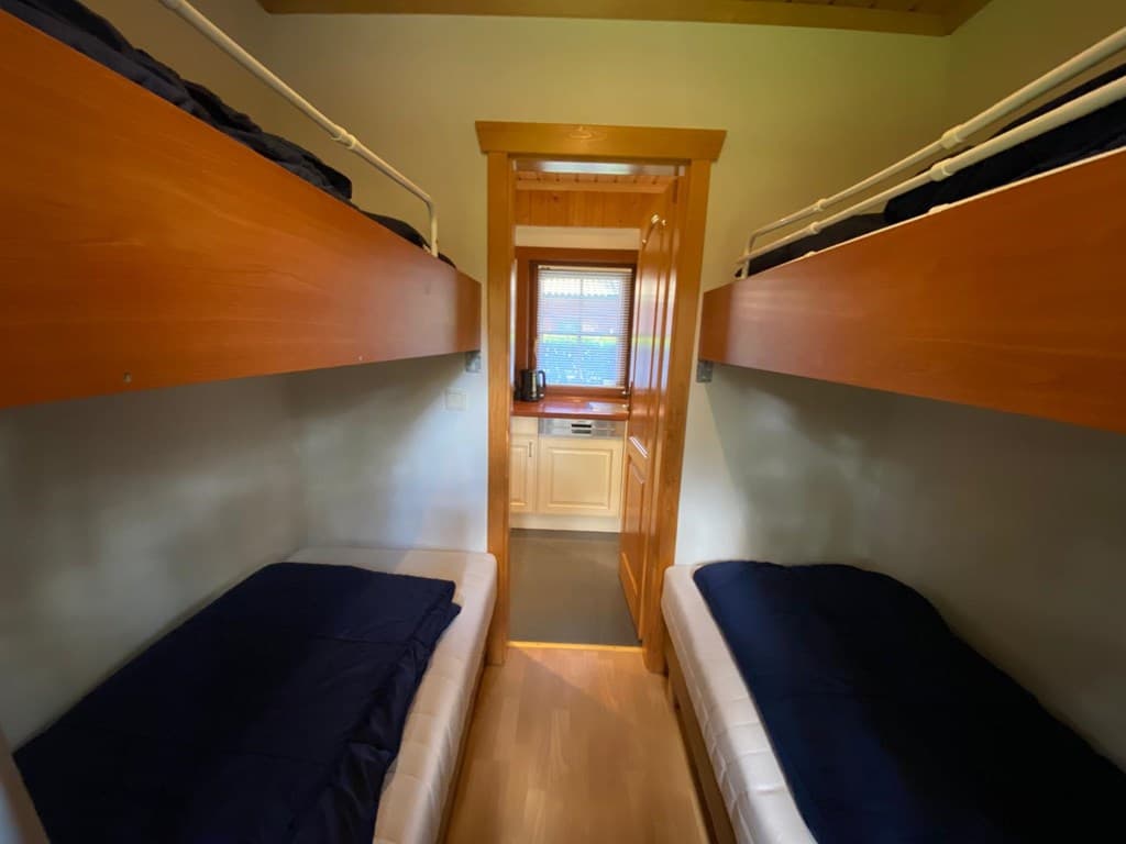 Slaapkamer met twee stapelbedden en toegang tot een keuken in de achtergrond