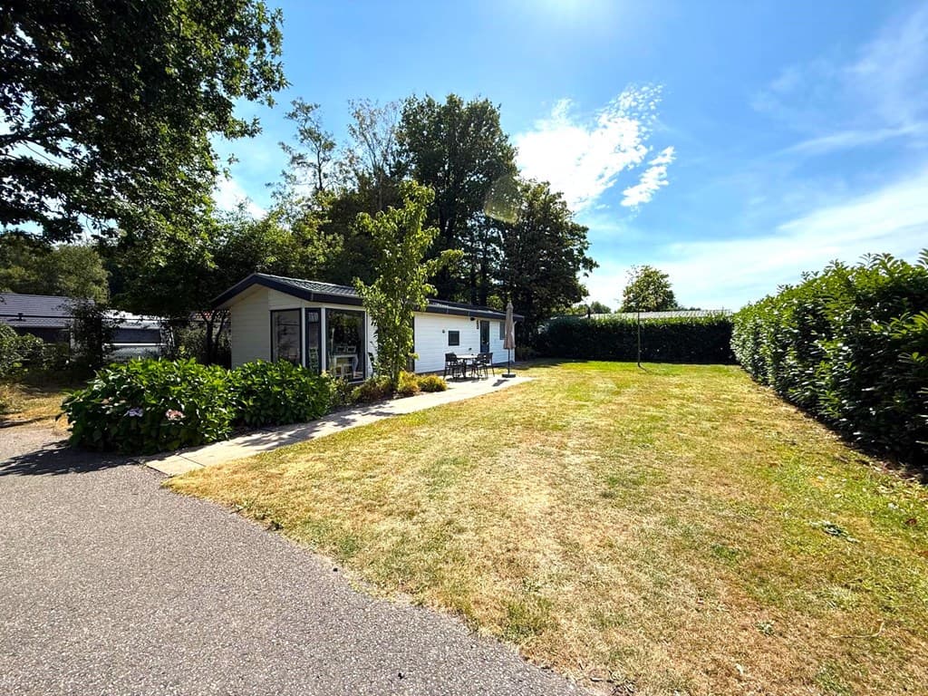 Vrijstaande woning met een ruime tuin en een terras, omgeven door bomen en struiken op EuroParcs Reestervallei