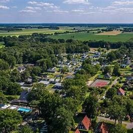 Luchtfoto van EuroParcs Reestervallei met vakantiewoningen, groen terrein en akkers op de achtergrond.