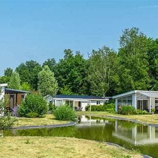 Landschappelijk uitzicht op vakantiewoningen rondom een vijver, omringd door groen en bomen