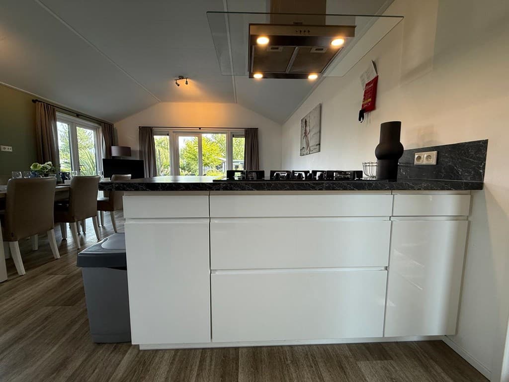 Moderne open keuken met een kookeiland en uitzicht op de eet- en zitkamer met grote ramen naar buiten
