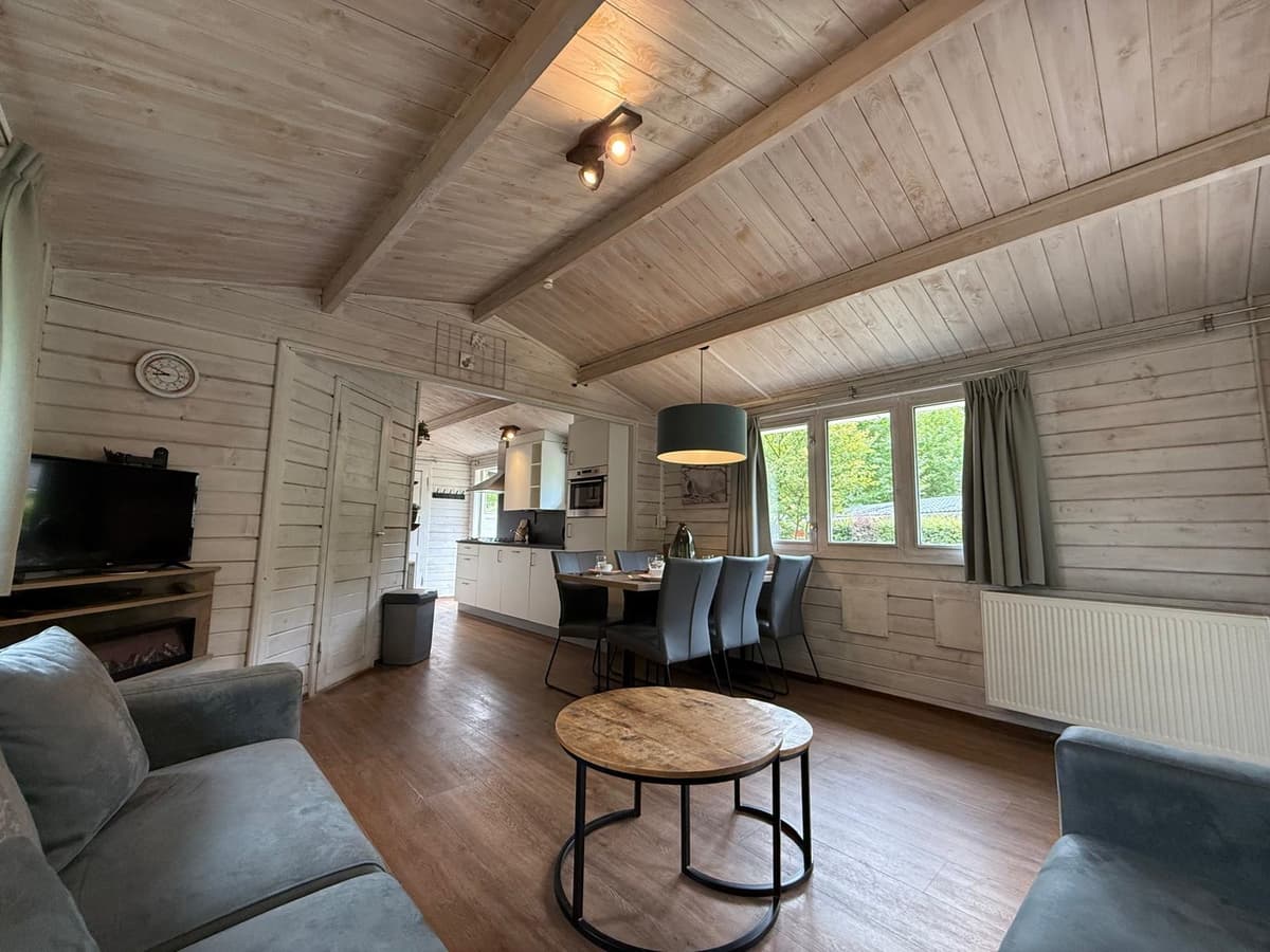 Moderne woonkamer met houten plafonds, eethoek en keukeninrichting, zachte kleuren en grote ramen voor natuurlijk licht