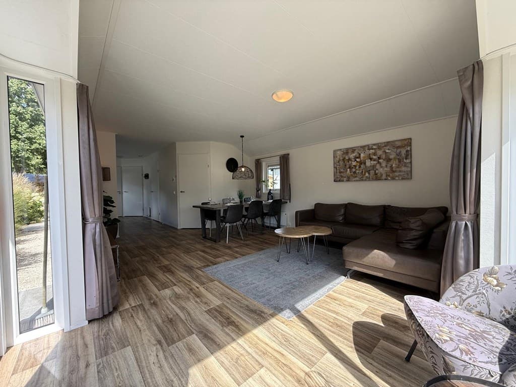 Moderne woonkamer met zithoek, eethoek en veel natuurlijk licht in EuroParcs Kaatsheuvel
