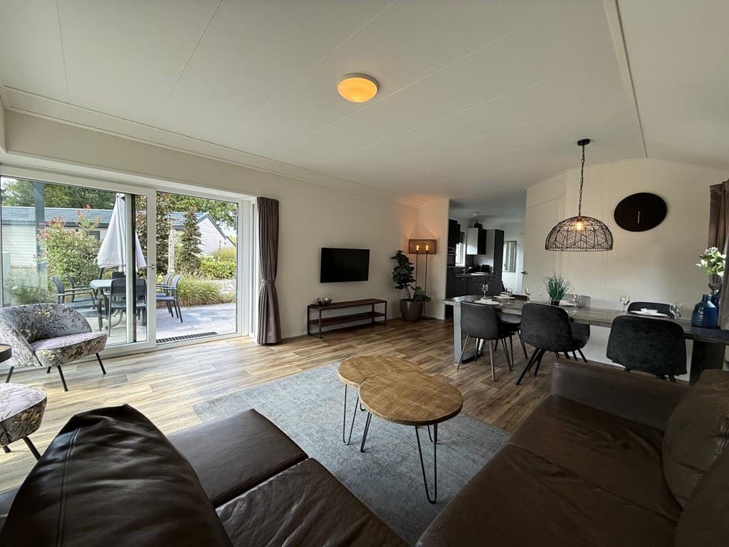 Moderne woonkamer met zithoek, eettafel en toegang tot de tuin met terras en meubels.