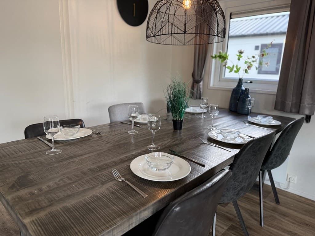 Eetkamertafel met opgemaakte borden, glazen en een groene plant in een sfeervolle ruimte bij EuroParcs Kaatsheuvel.