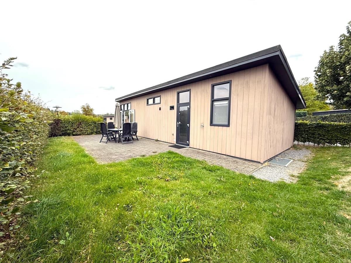 Moderne vakantiewoning met een terras, een groene tuin en een lichtgekleurde gevel in een rustgevende omgeving