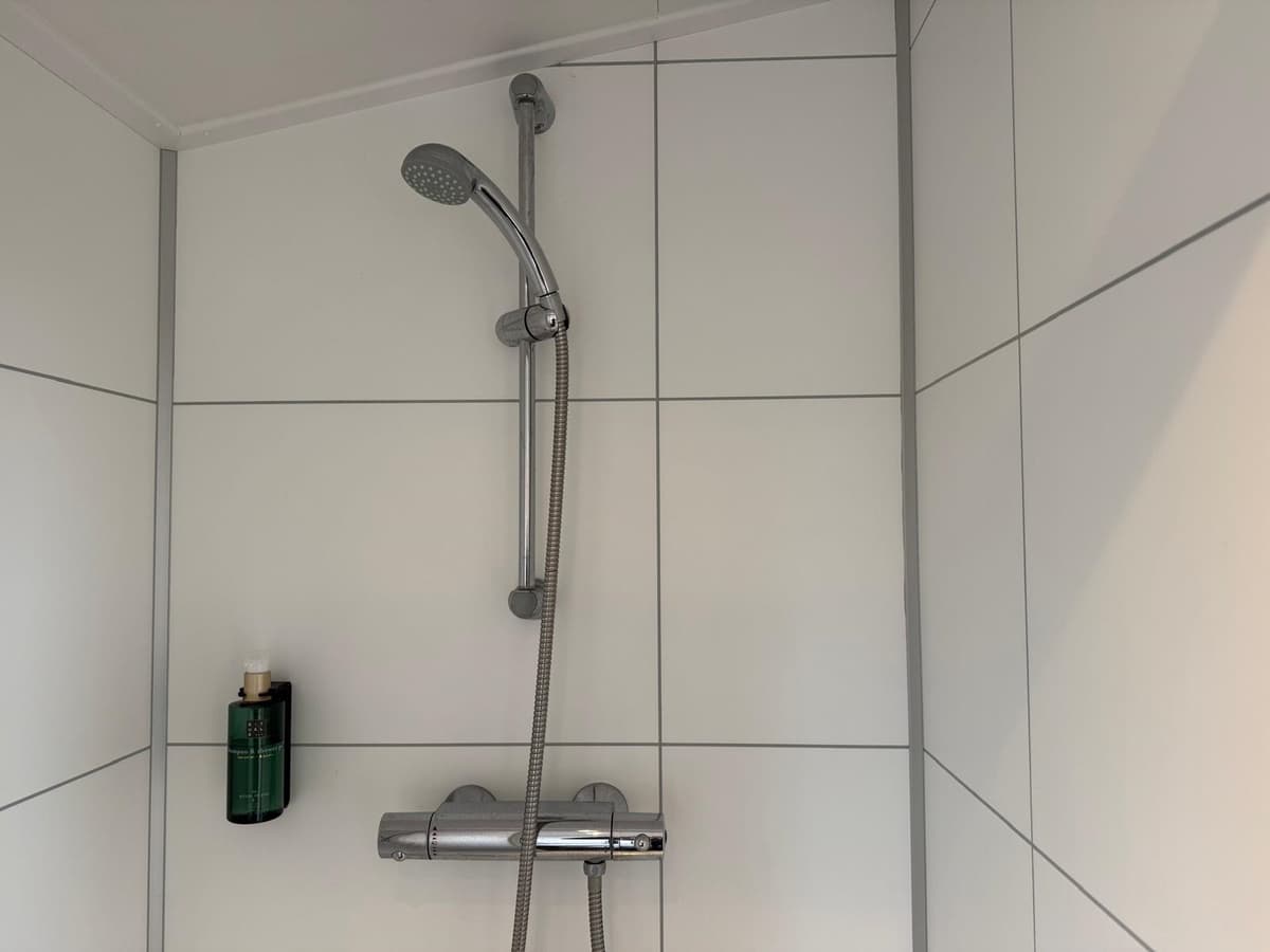 Douche met moderne wandtegels en een regendouchekop aan de muur
