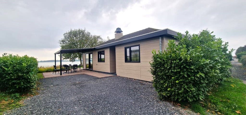 Vakantiehuis met overdekt terras, omringd door groen en uitzicht op water bij EuroParcs De Biesbosch.