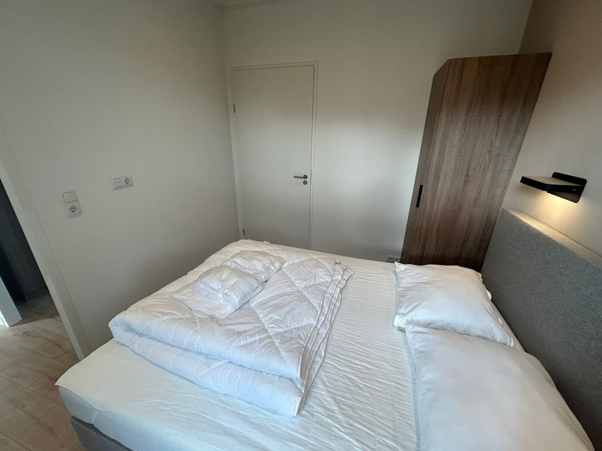 Slaapkamer met een tweepersoonsbed, kastenwand en een deur naar de gang.