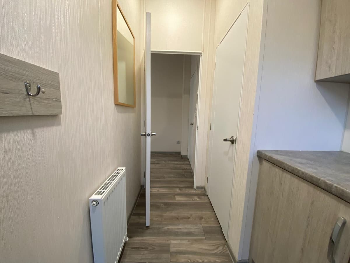 Inkomhal met een radiator, deuren naar andere ruimtes en een muur met een kapstok.