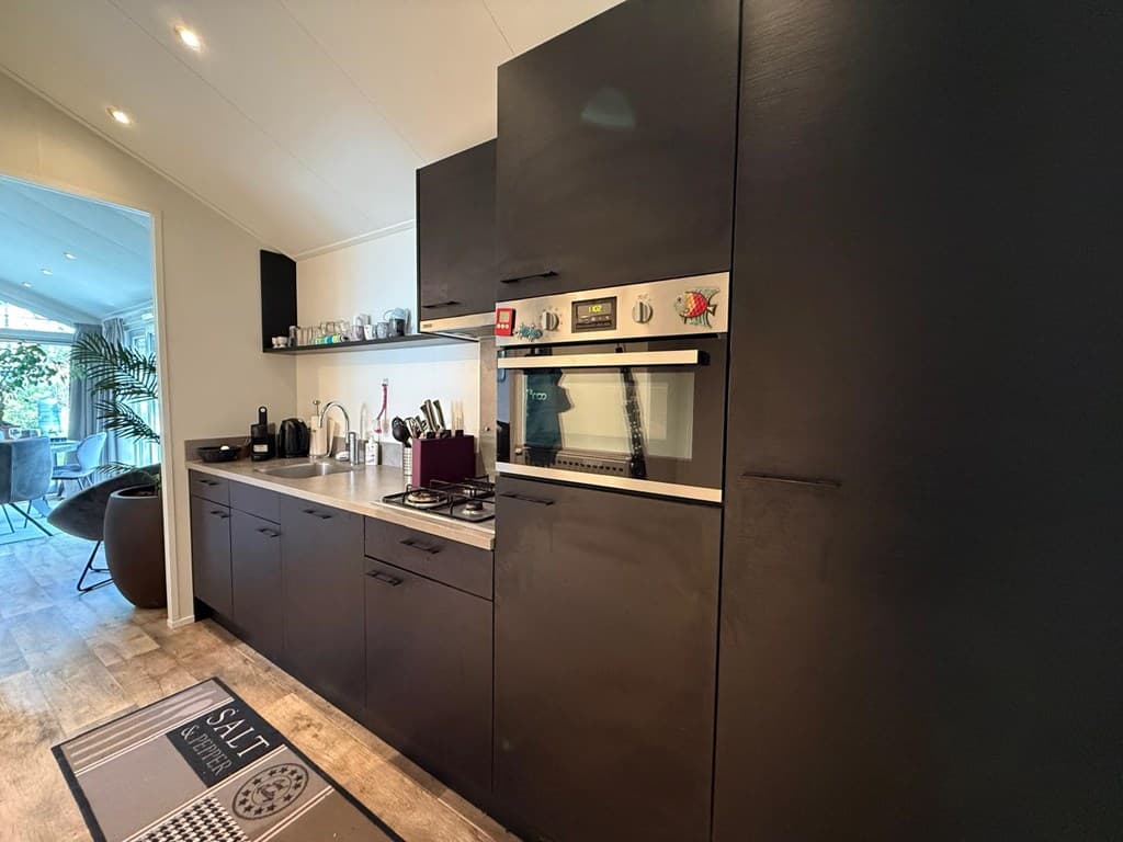 Moderne keuken met zwarte kasten, oven, kookplaat en diverse keukenapparaten in EuroParcs Resort De Utrechtse Heuvelrug.