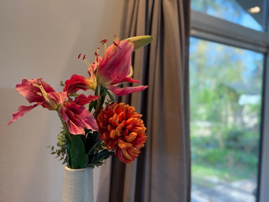 Vaas met kleurrijke bloemen en een raam met uitzicht op de natuur op de achtergrond