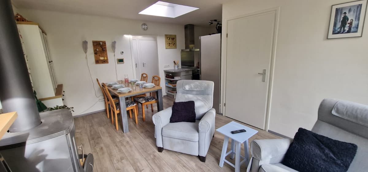 Gezellige woonkamer met eetgedeelte, twee comfortabele stoelen en moderne inrichting.