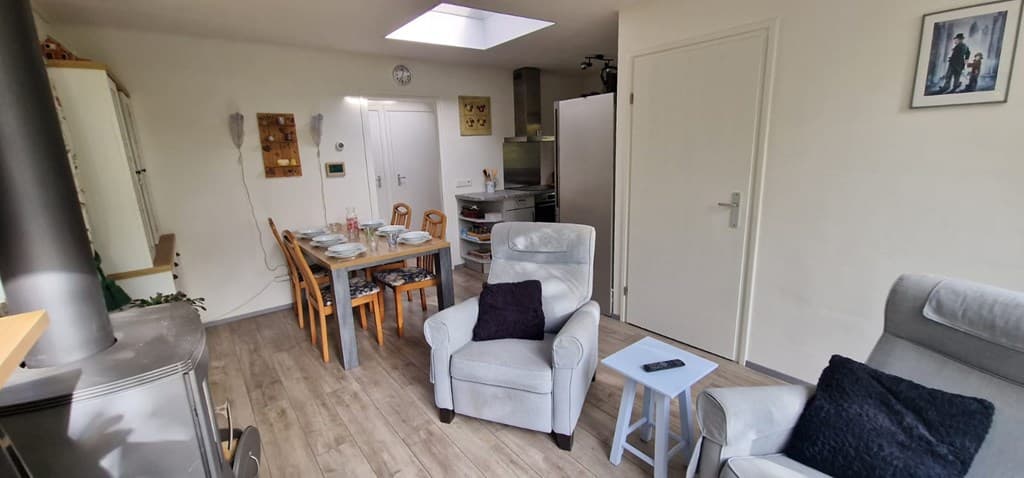 Gezellige woonkamer met eetgedeelte, twee comfortabele stoelen en moderne inrichting.