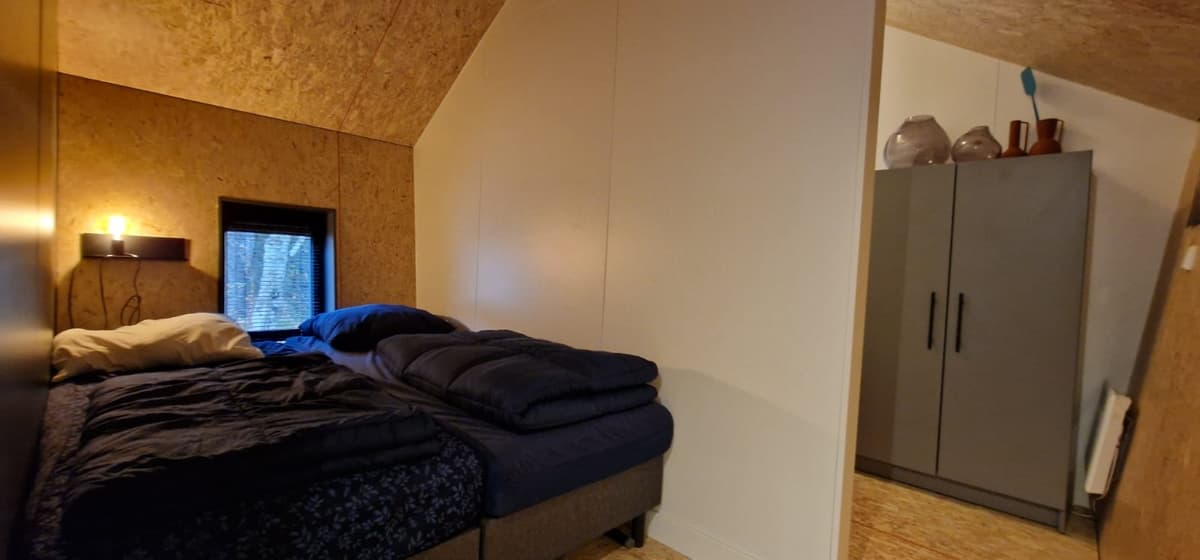 Slaapkamer met twee eenpersoonsbedden, een raam en een kast tegen de muur