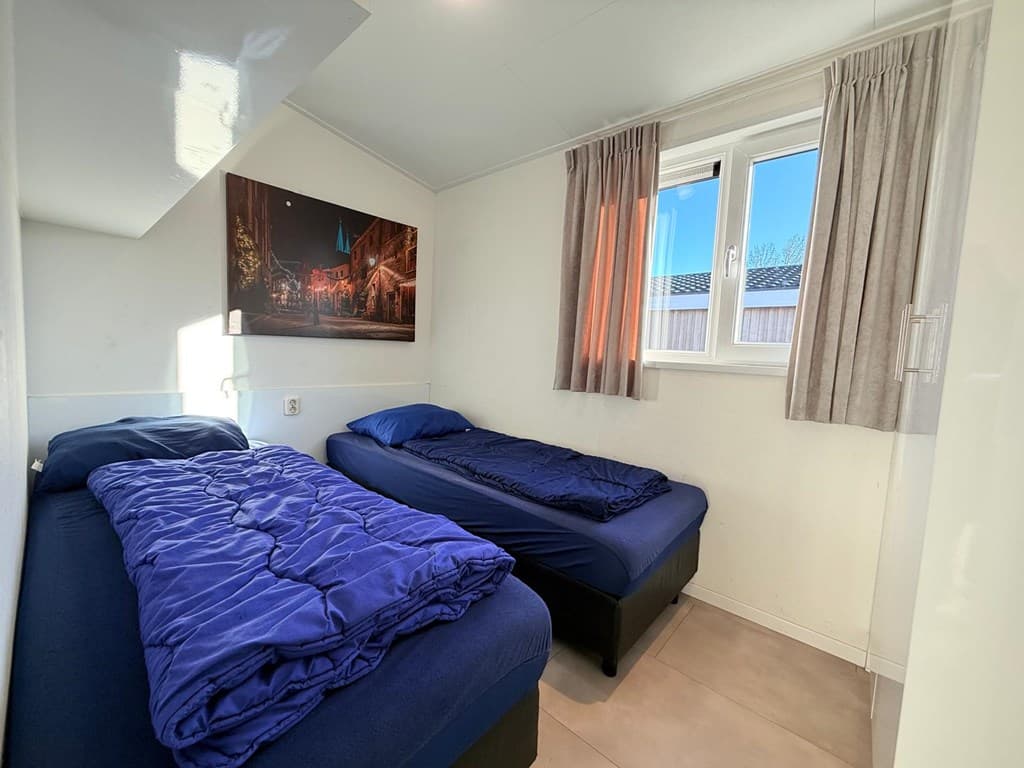 Slaapkamer met twee apart bedden, raam met uitzicht en een schilderij aan de muur