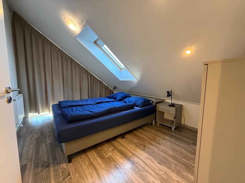 Slaapkamer met schuin dak, twee eenpersoonsbedden, kledingkast en raam met dakraam.