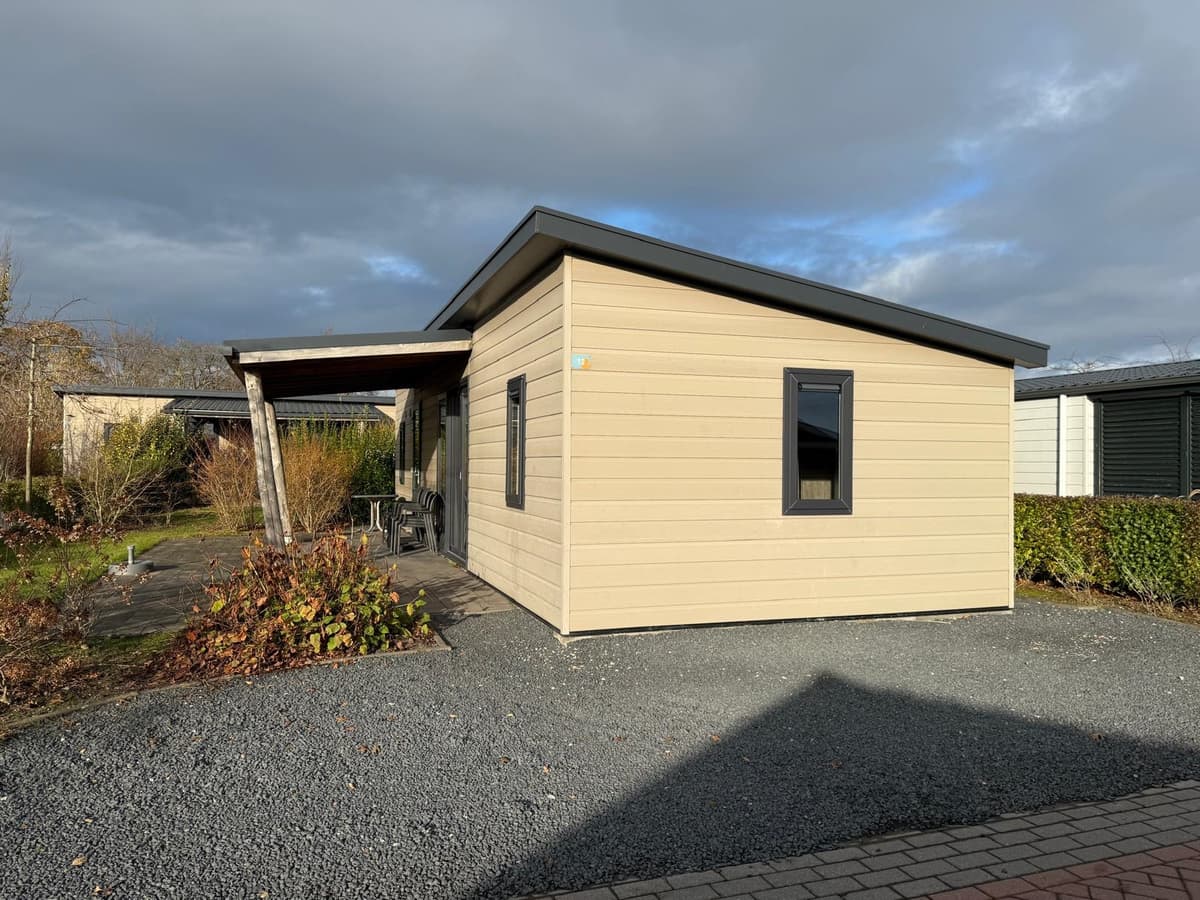 Lichte woning met een hellend dak, gelegen op een gravelperceel met een terras en groene beplanting.