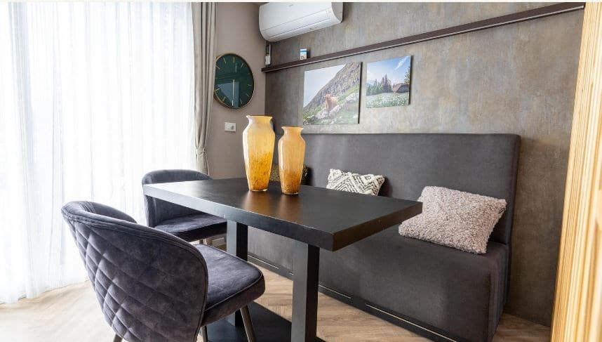 Eetruimte met een zwart tafelblad, twee paarse stoelen en vazen op tafel, lichtinval door grote ramen