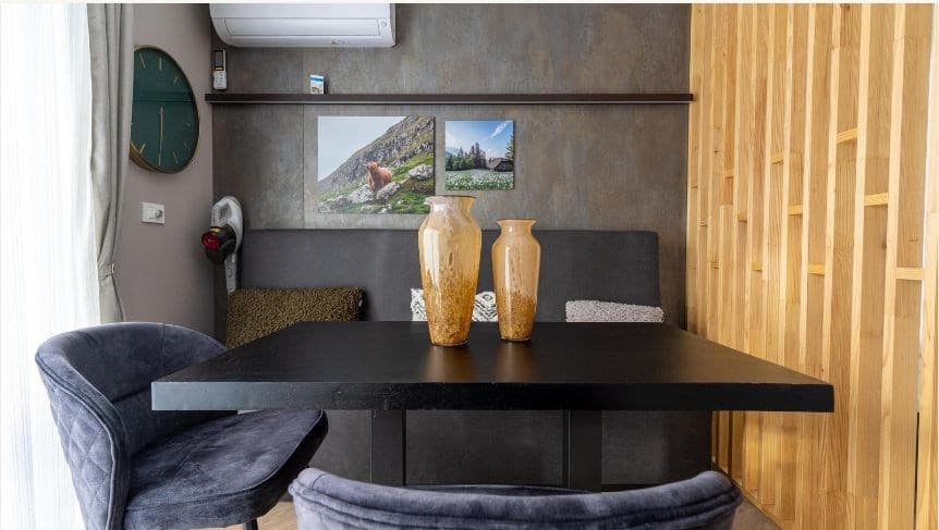 Eettafel met twee vazen en stoelen in een moderne woonkamer met houtaccenten en muurdecoratie