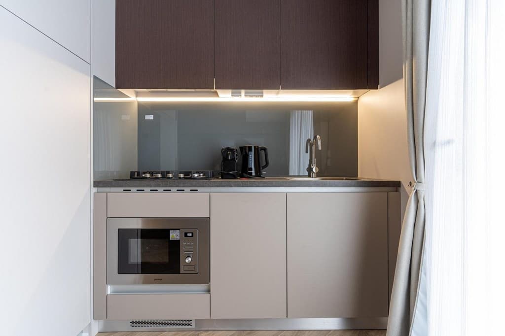 Moderne keuken met inbouwapparatuur, waaronder een kookplaat, magnetron en koffiezetapparaat.