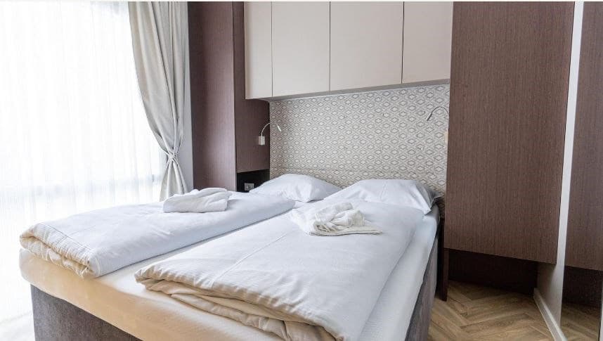 Slaapkamer met twee aparte bedden, beige beddengoed en een wandkast in een lichte, moderne stijl.