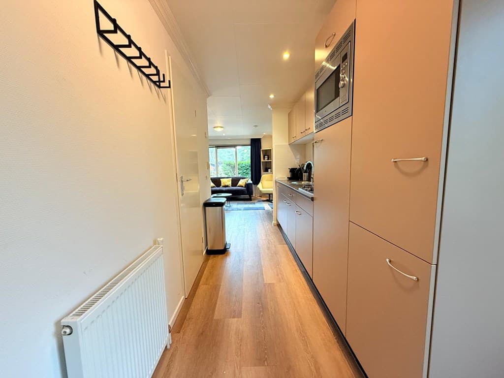 Ruime hal met toegang tot de keuken en woonkamer, voorzien van moderne meubels en veel natuurlijk licht