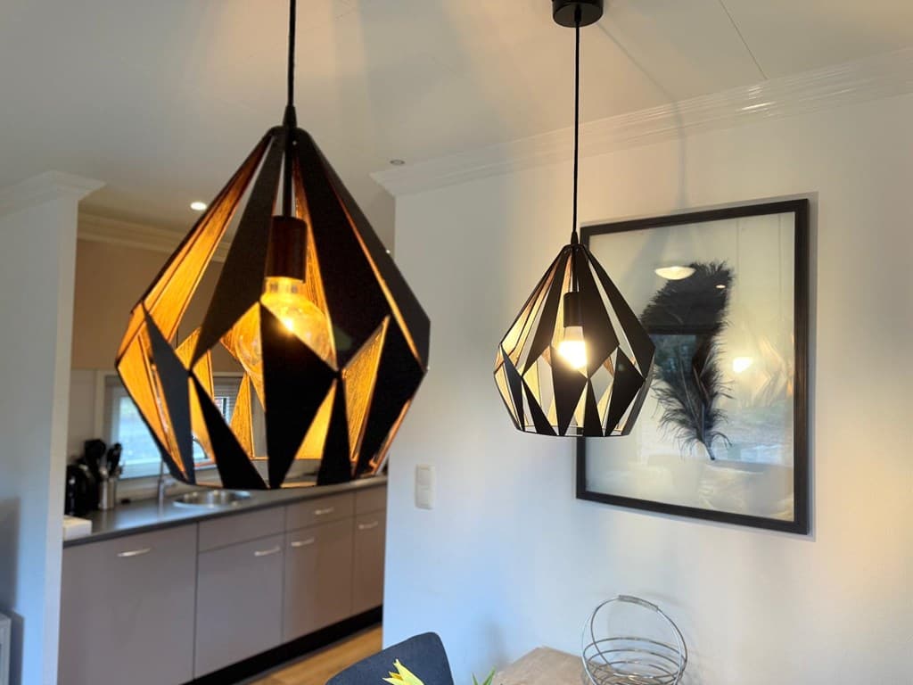 Hedendaagse interieur met twee stijlvolle hanglampen en een kunstwerk aan de muur in een lichte woning