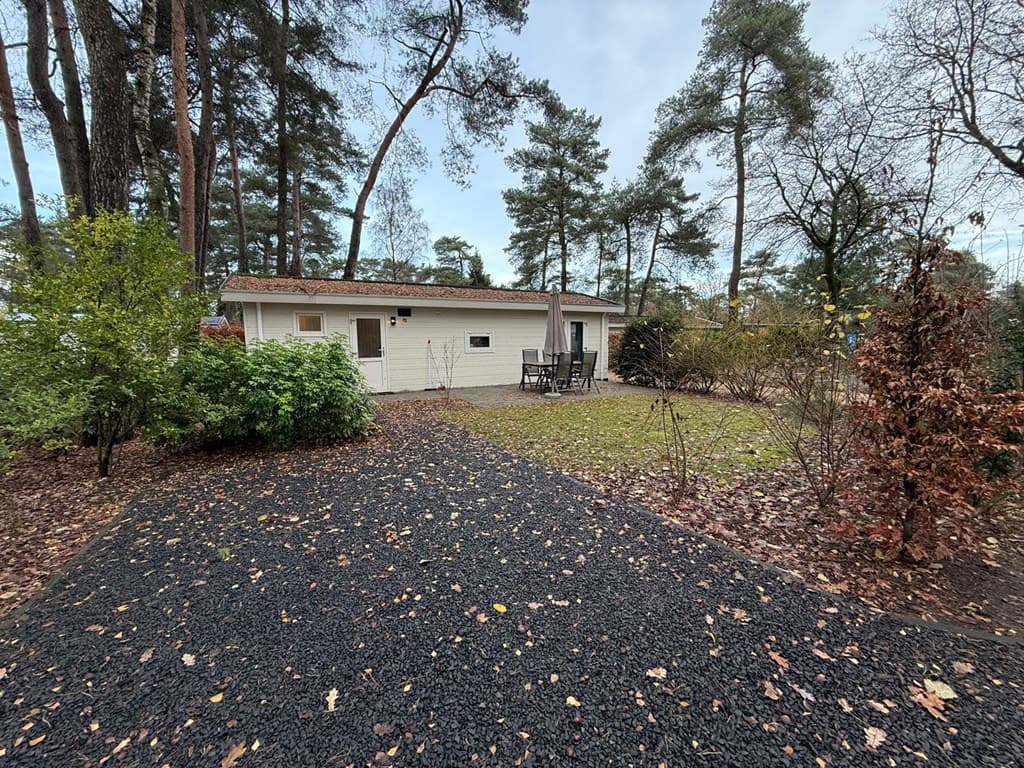 Woning met tuin en terras omringd door bomen en struiken op EuroParcs De Zanding in Otterlo