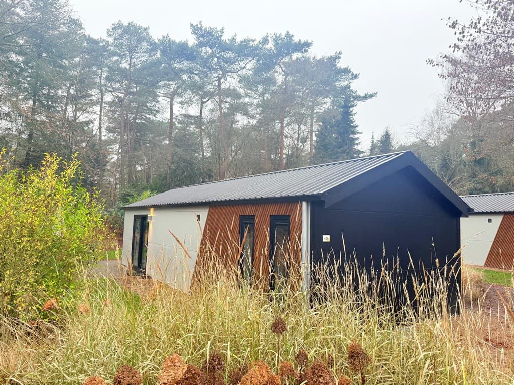 Moderne vakantiewoning met houten accenten, omringd door bomen en gras op EuroParcs Resort De Utrechtse Heuvelrug.