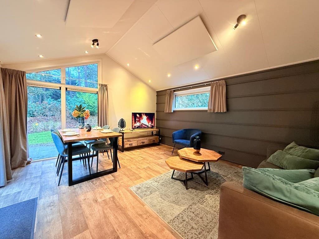Zithoek met banken, eettafel en grote ramen met uitzicht op de tuin in een moderne woonkamer