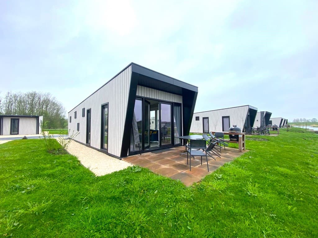 Moderne vakantiewoning met schuin dak, grote ramen en terras, gelegen op een grasveld bij EuroParcs De IJssel Eilanden.