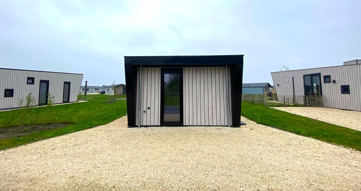 Moderne vakantiewoning met houten gevel, omringd door gras en grindpaden, gelegen in EuroParcs De IJssel Eilanden