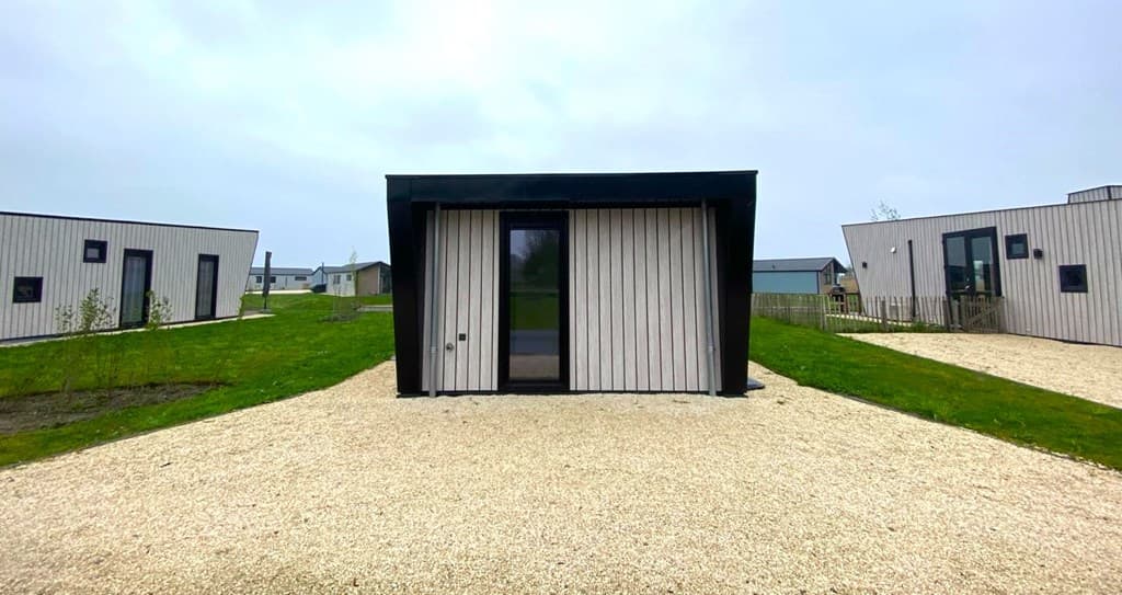 Moderne vakantiewoning met houten gevel, omringd door gras en grindpaden, gelegen in EuroParcs De IJssel Eilanden