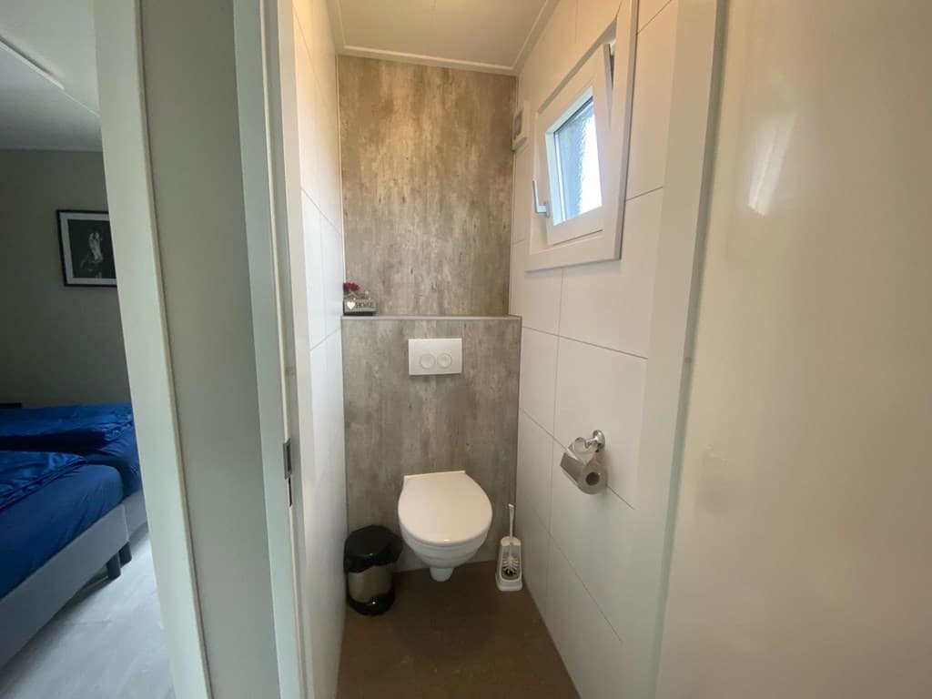 Kleine badkamer met toilet, wastafel en een raam voor natuurlijke lichtinval