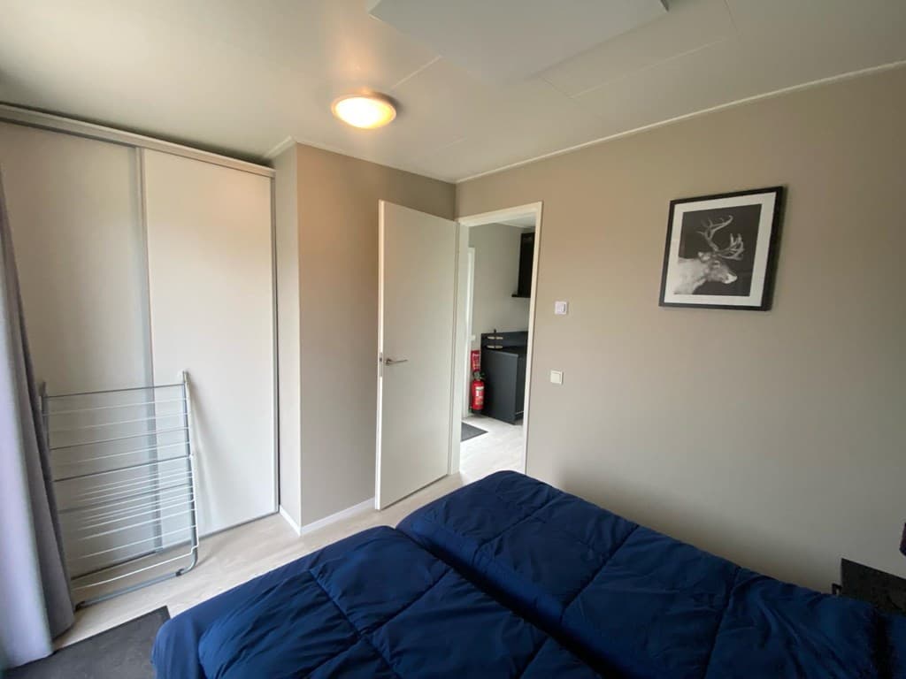 Slaapkamer met een tweepersoonsbed, kast, deur naar de gang en uitzicht op de keukenruimte.