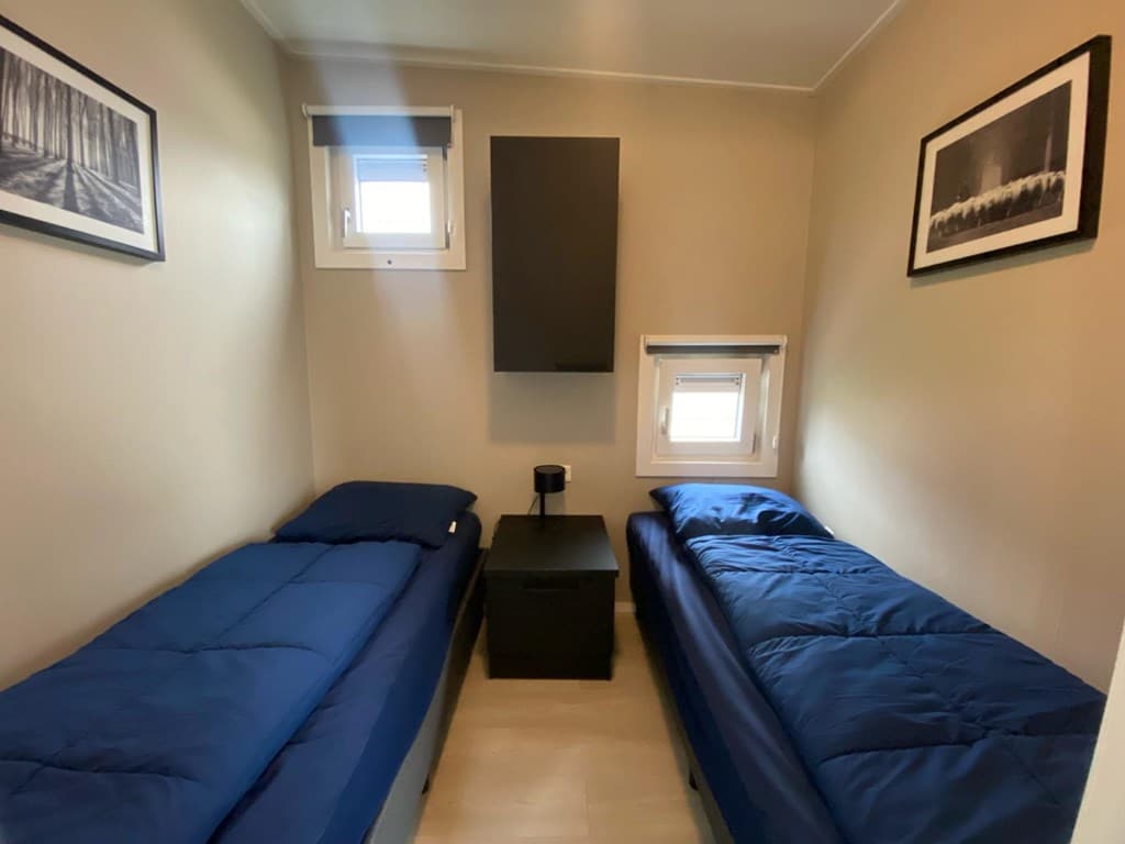 Slaapkamer met twee eenpersoonsbedden, nachtkastje en muurdecoratie, lichtinval van twee ramen