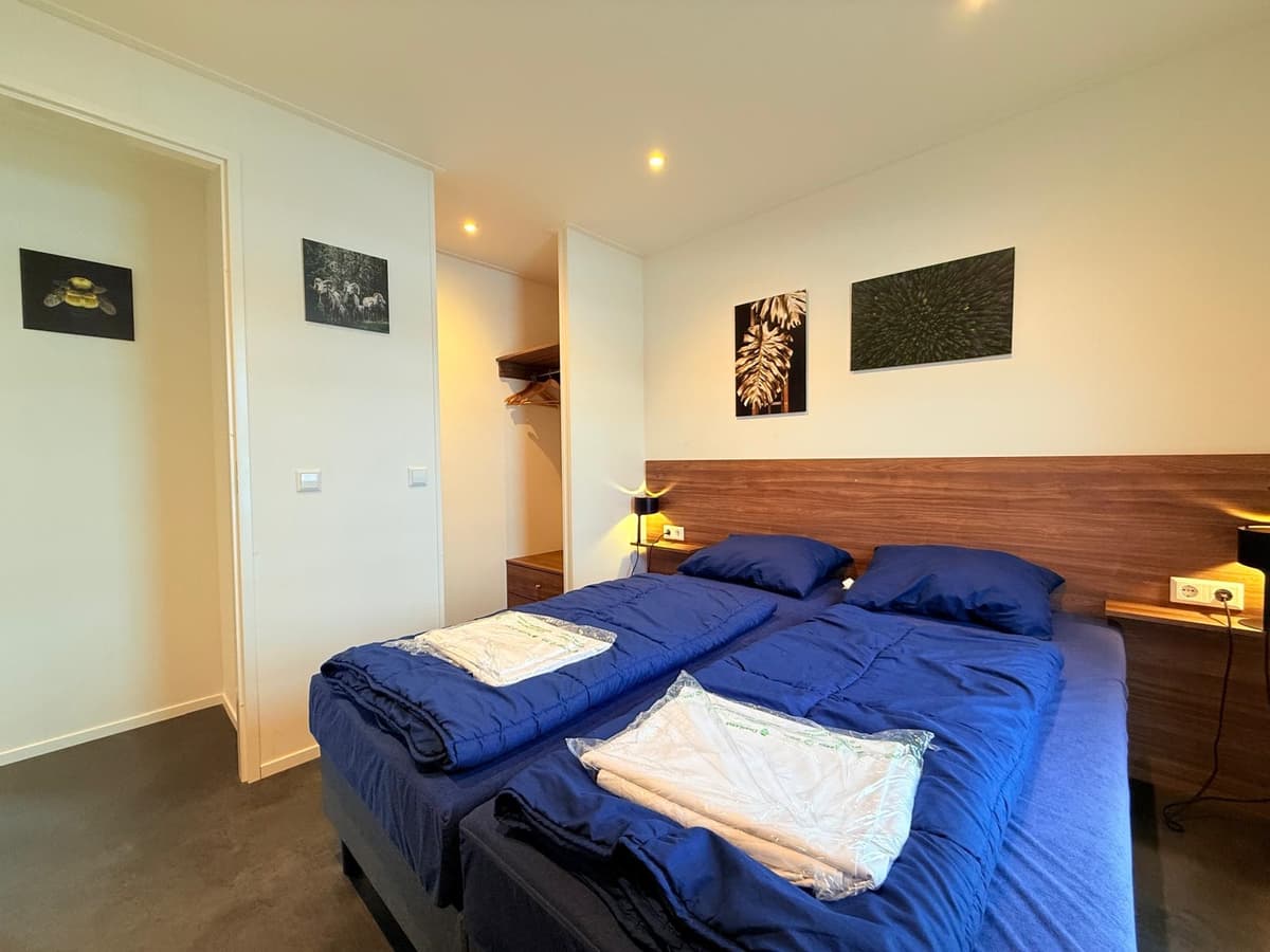 Slaapkamer met twee eenpersoonsbedden, nachtkastjes en muurdecoraties in een moderne inrichting