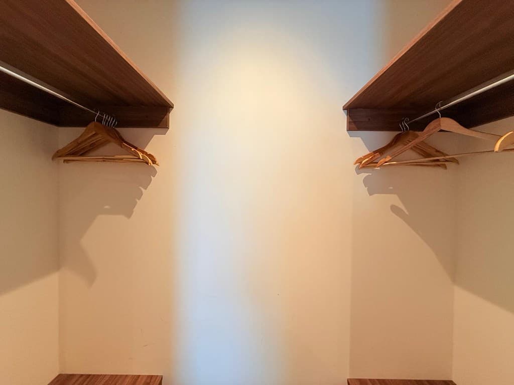 Inloopkast met twee planken en houten hangers aan beide zijden van de wand