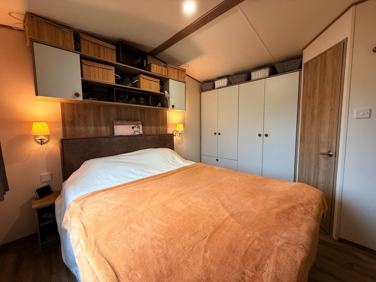 Slaapkamer met een groot bed, wandkasten en zachte verlichting in een recreatiewoning.