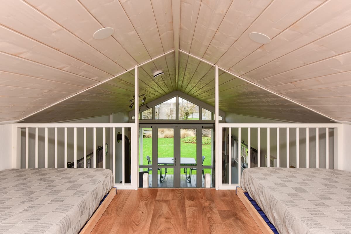 Uitzicht vanuit de bovenverdieping op een woonkamer met grote ramen en toegang tot de tuin.