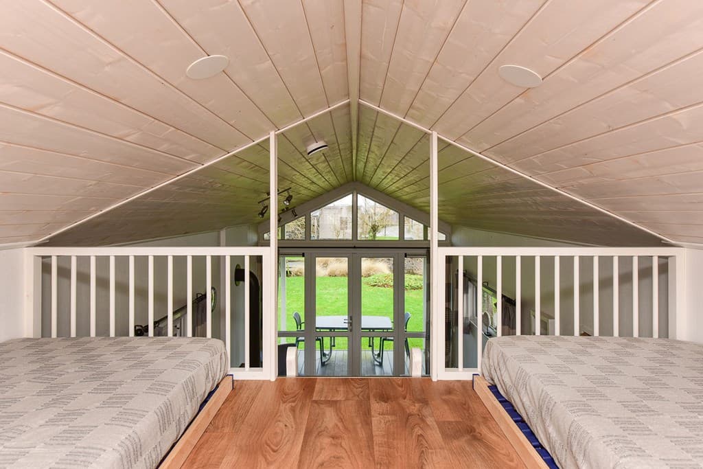 Uitzicht vanuit de bovenverdieping op een woonkamer met grote ramen en toegang tot de tuin.