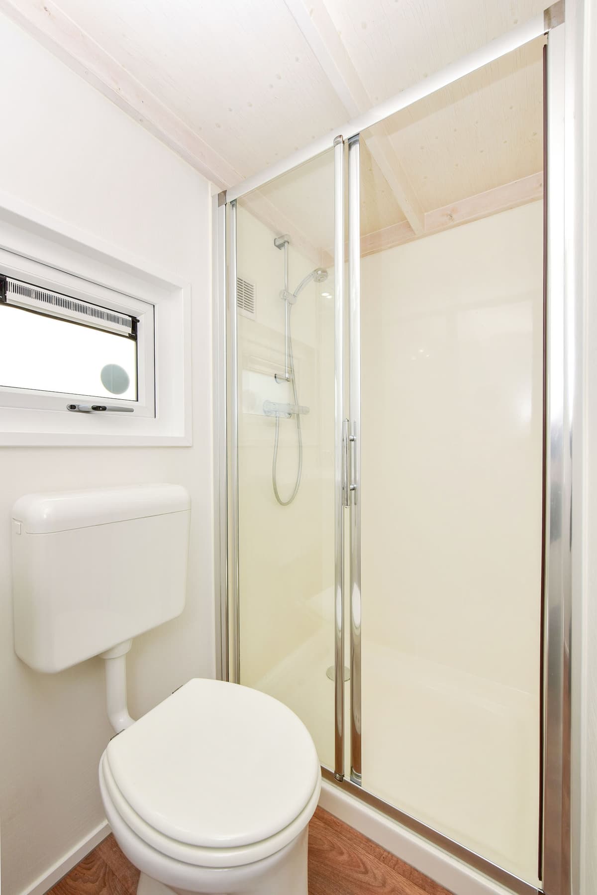 Badkamer met douchecabine, toilet en raam voor ventilatie.