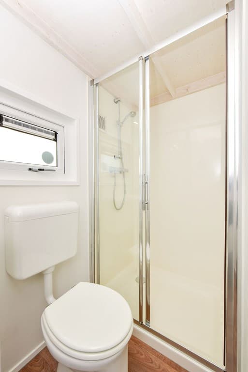 Badkamer met douchecabine, toilet en raam voor ventilatie.