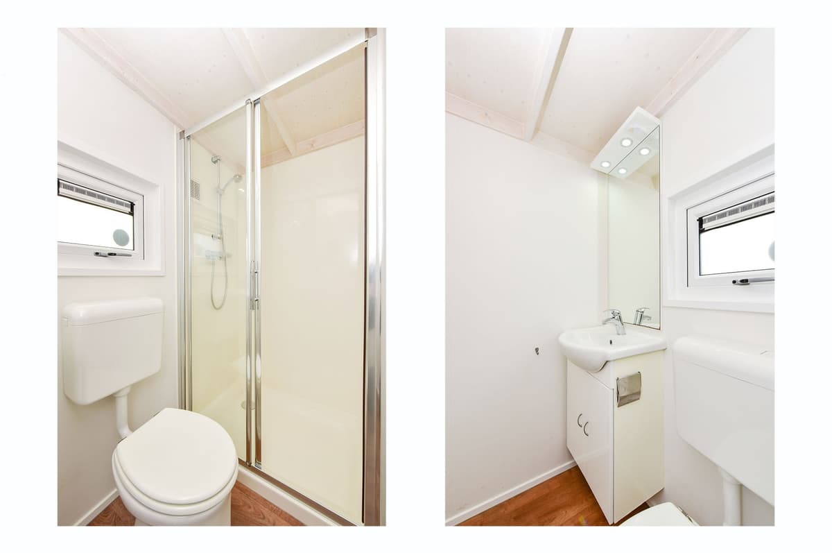 Moderne badkamer met douchecabine, toilet en wastafel in lichte kleurstelling met houten vloer.